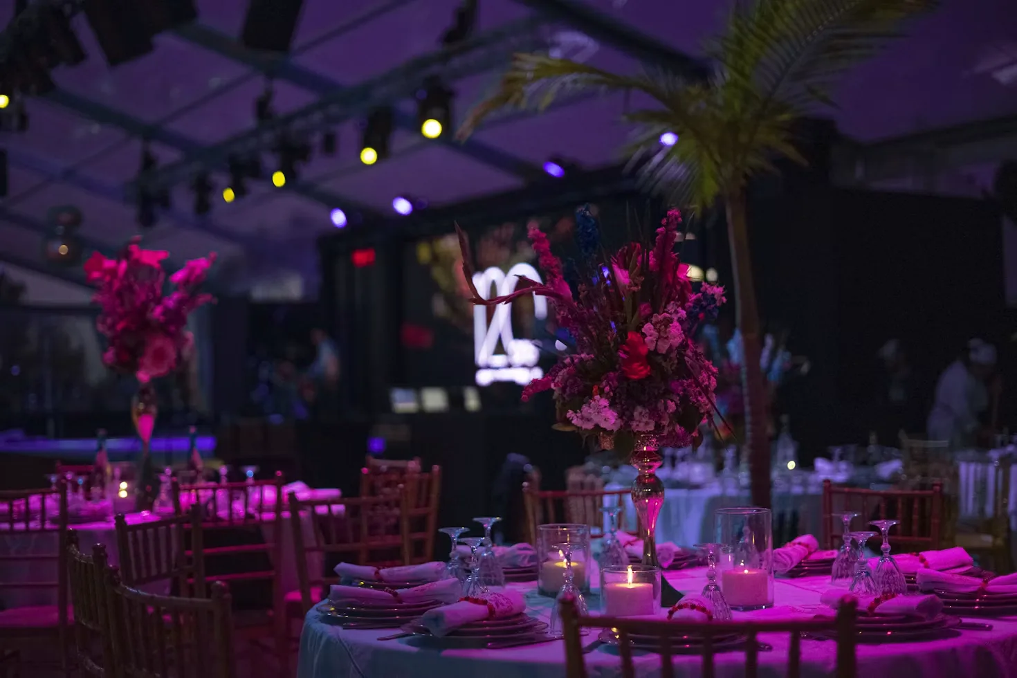 Corporate event venue with candlelit tables, floral centrepieces and colourful lighting