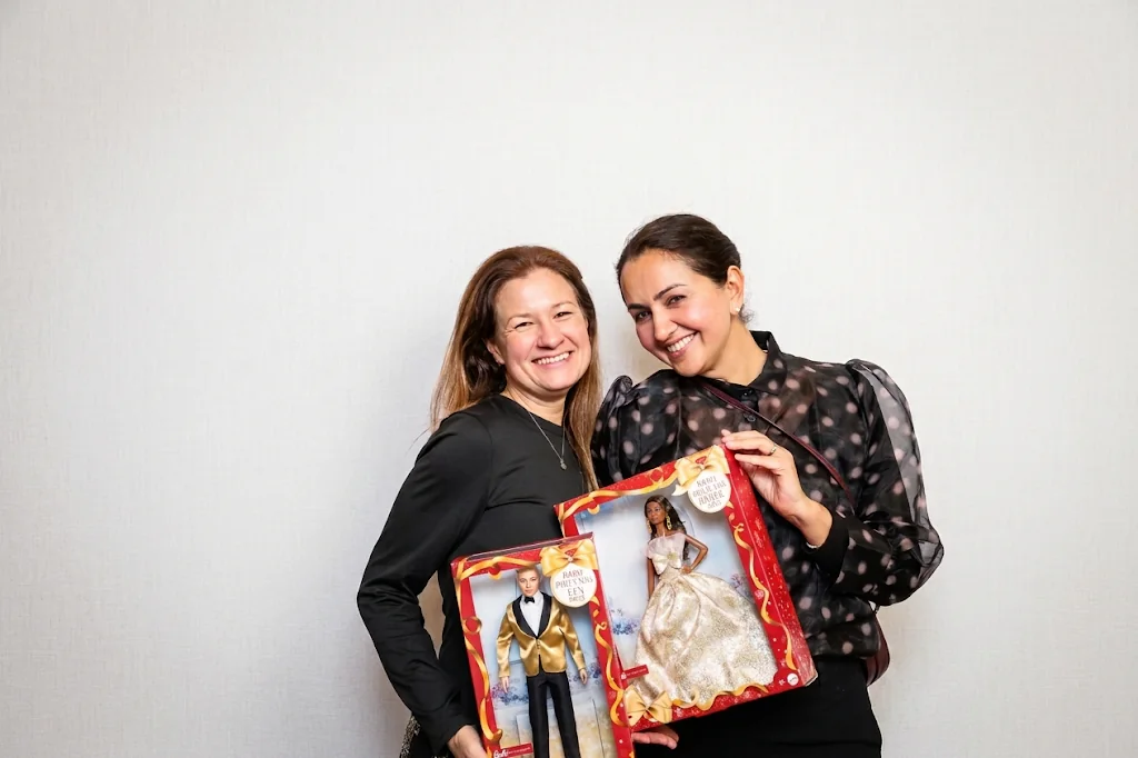 Two guests posing with gifts at a branded photo booth experience